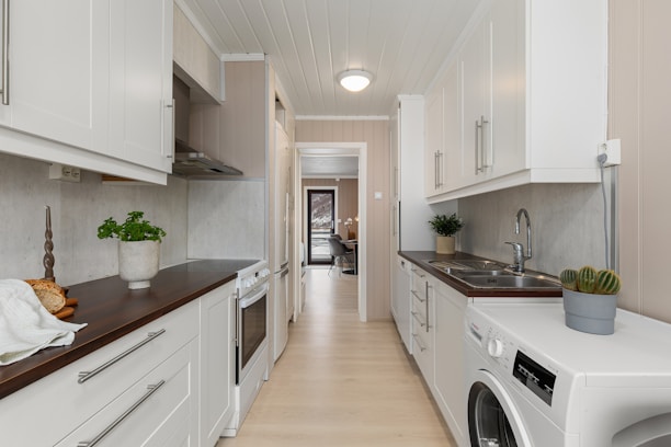 A long narrow kitchen with a washer and dryer