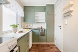 A kitchen with green cabinets and white appliances