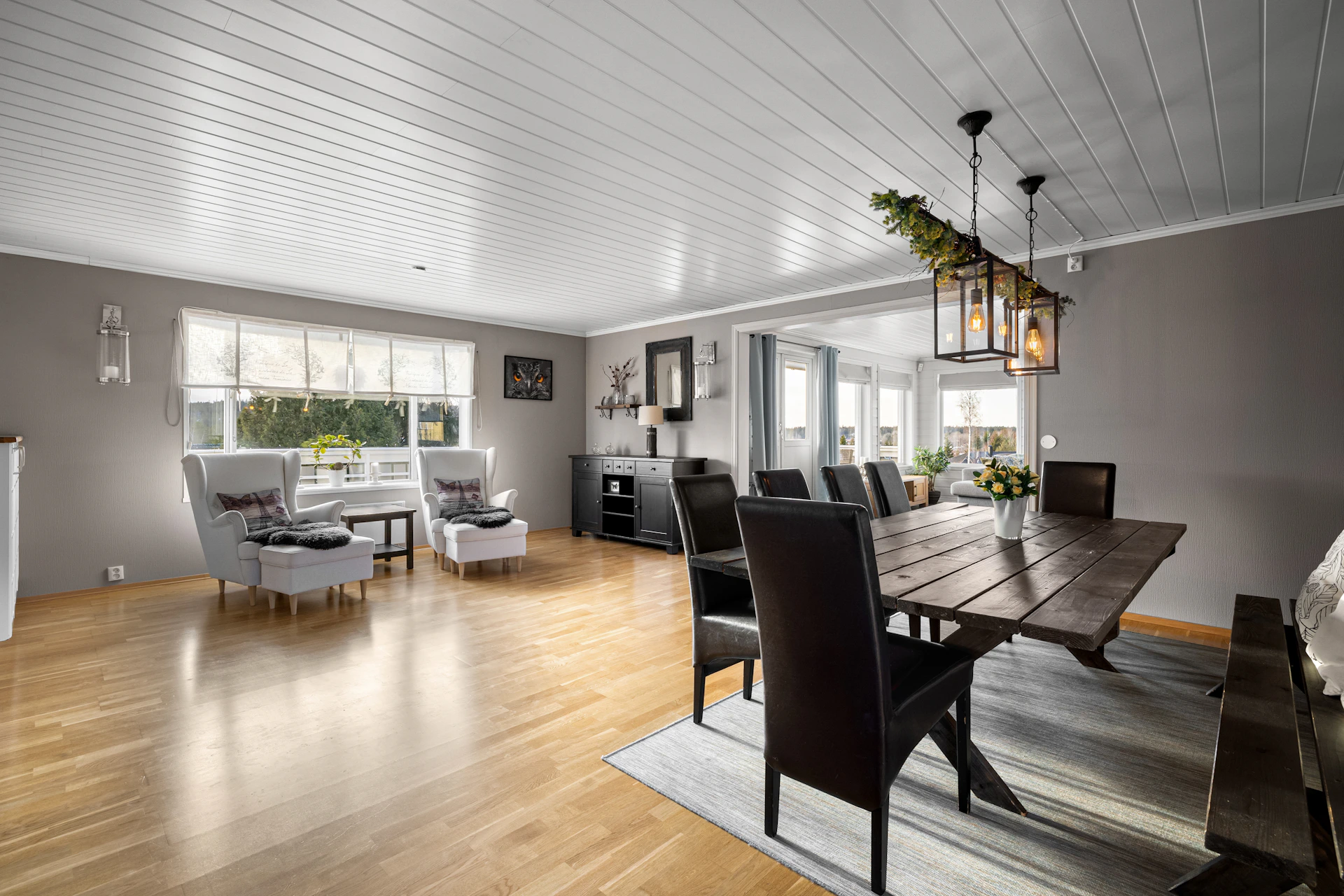A dining room with a large wooden table and chairs