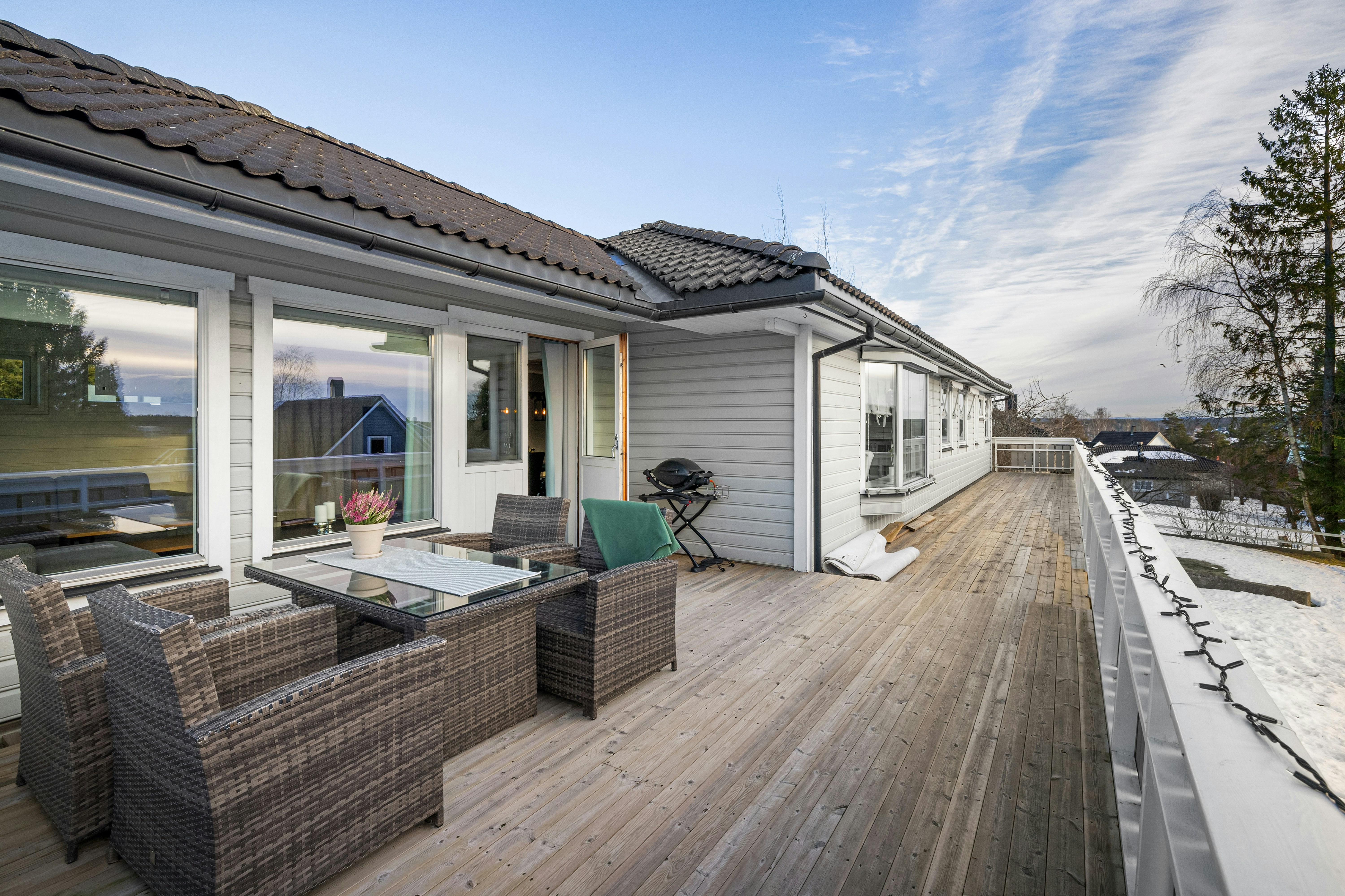 A deck with wicker furniture and a table and chairs