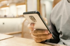 A person sitting at a table with a cell phone