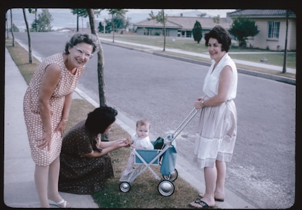 Two women and a baby in a stroller on a sidewalk