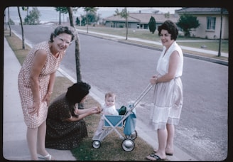Two women and a baby in a stroller on a sidewalk