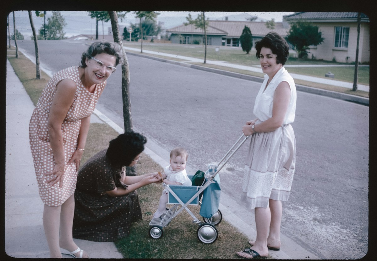 Two women walk on a sidewalk with a baby in a stroller, illustrating kindergarten parent tips for morning routines.