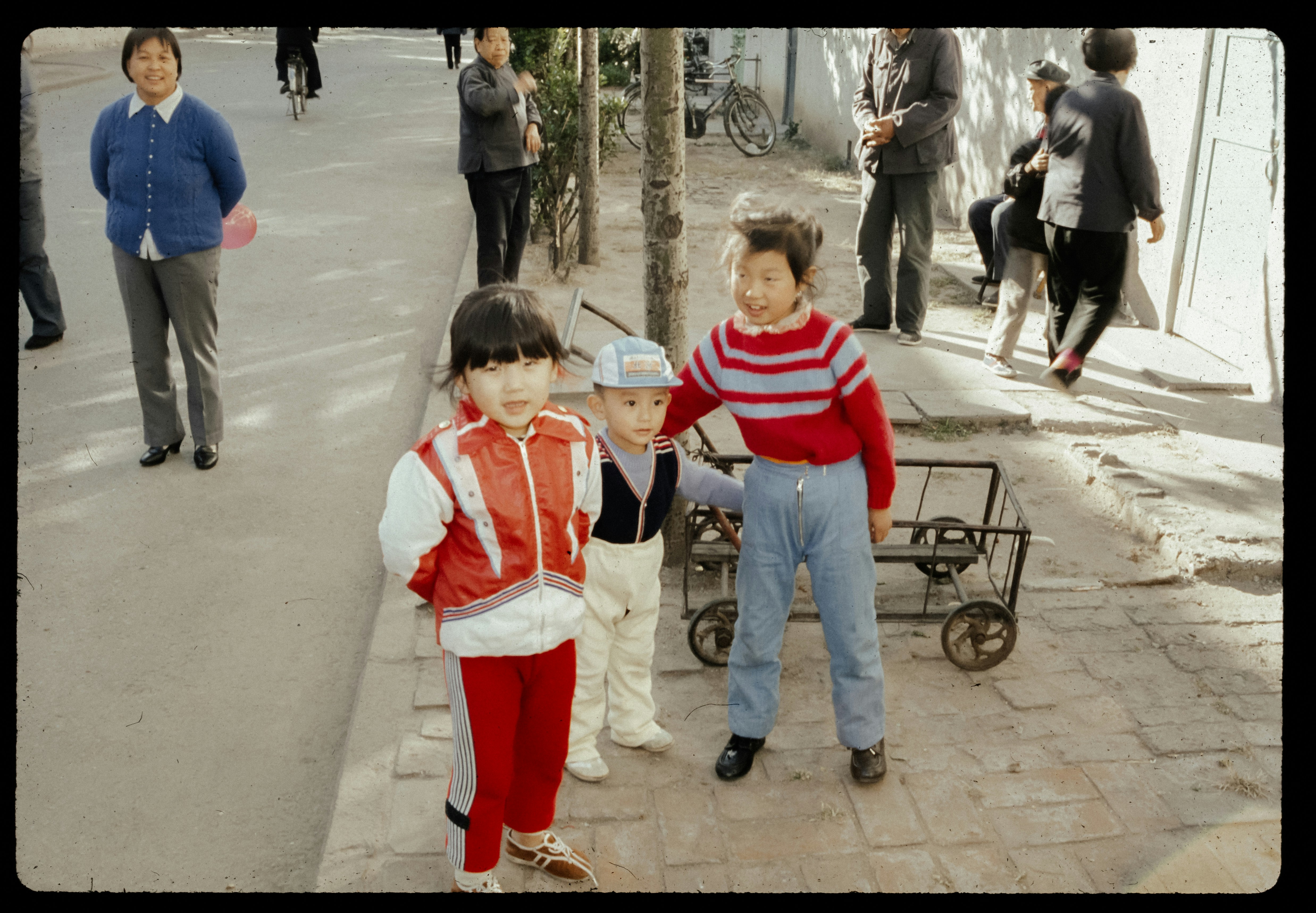 A couple of kids standing next to each other on a sidewalk
