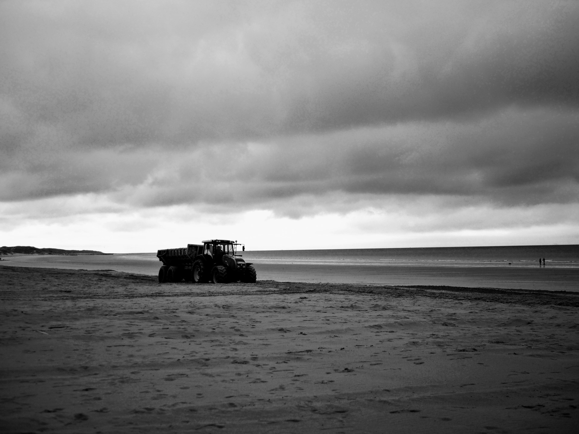 A black and white photo of a tractor on a beach