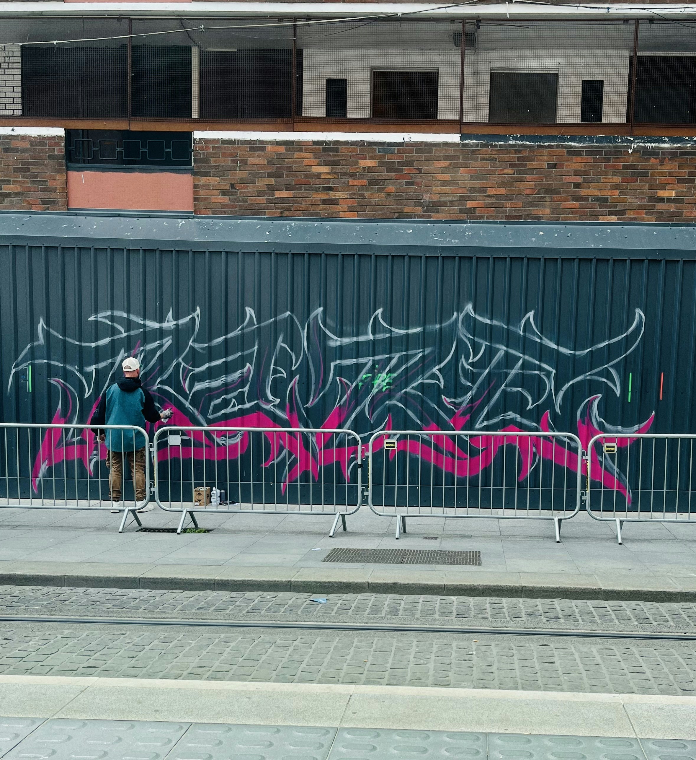 A man standing next to a fence with graffiti on it