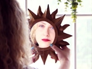 A woman is looking in a mirror at herself