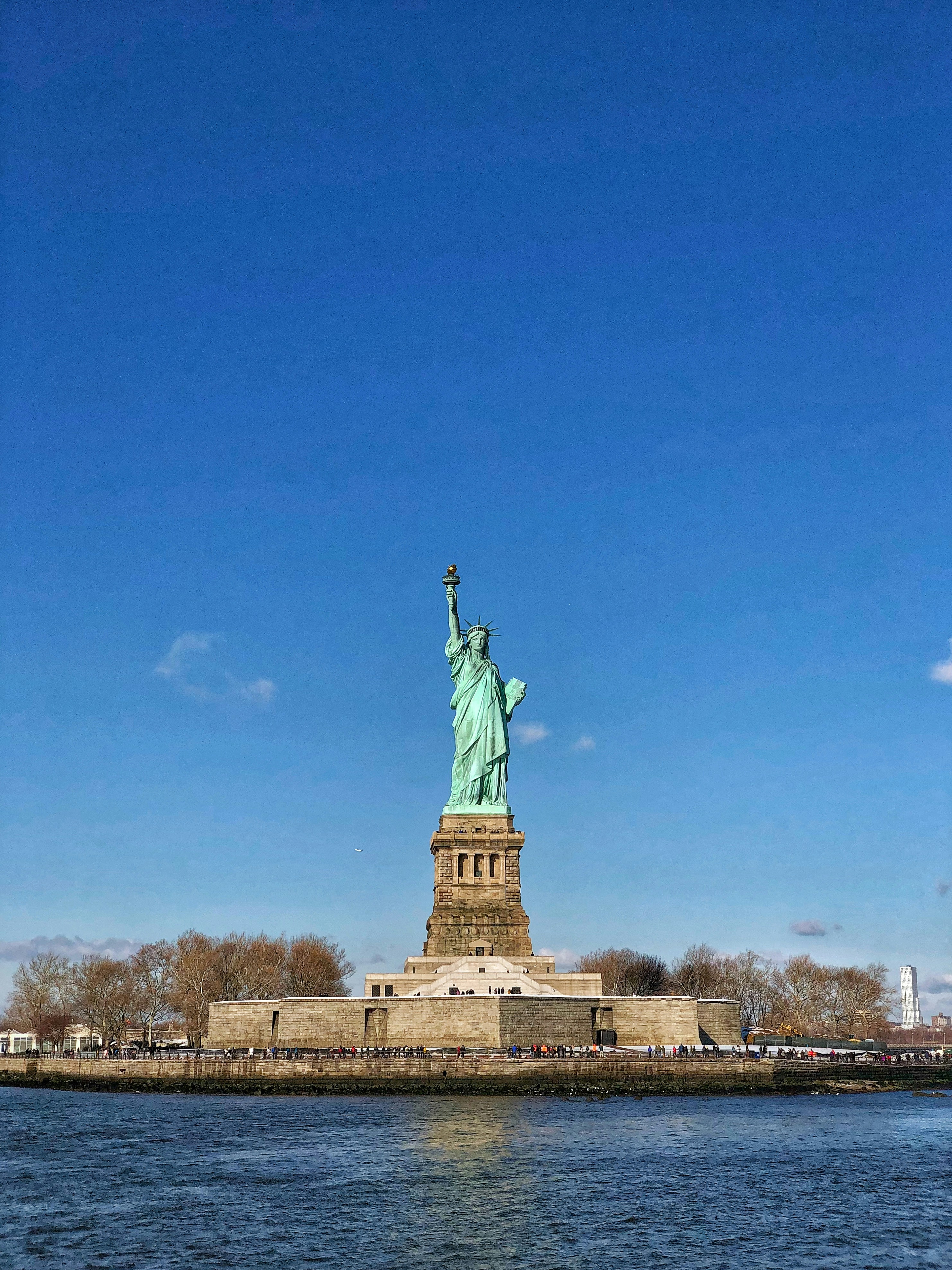The statue of liberty stands in the middle of the water