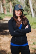 A woman standing in the woods with her arms crossed