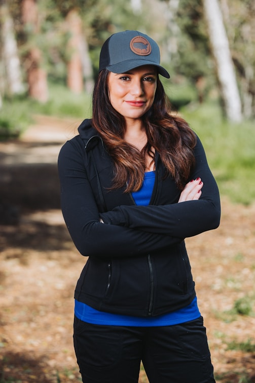 A woman standing in the woods with her arms crossed