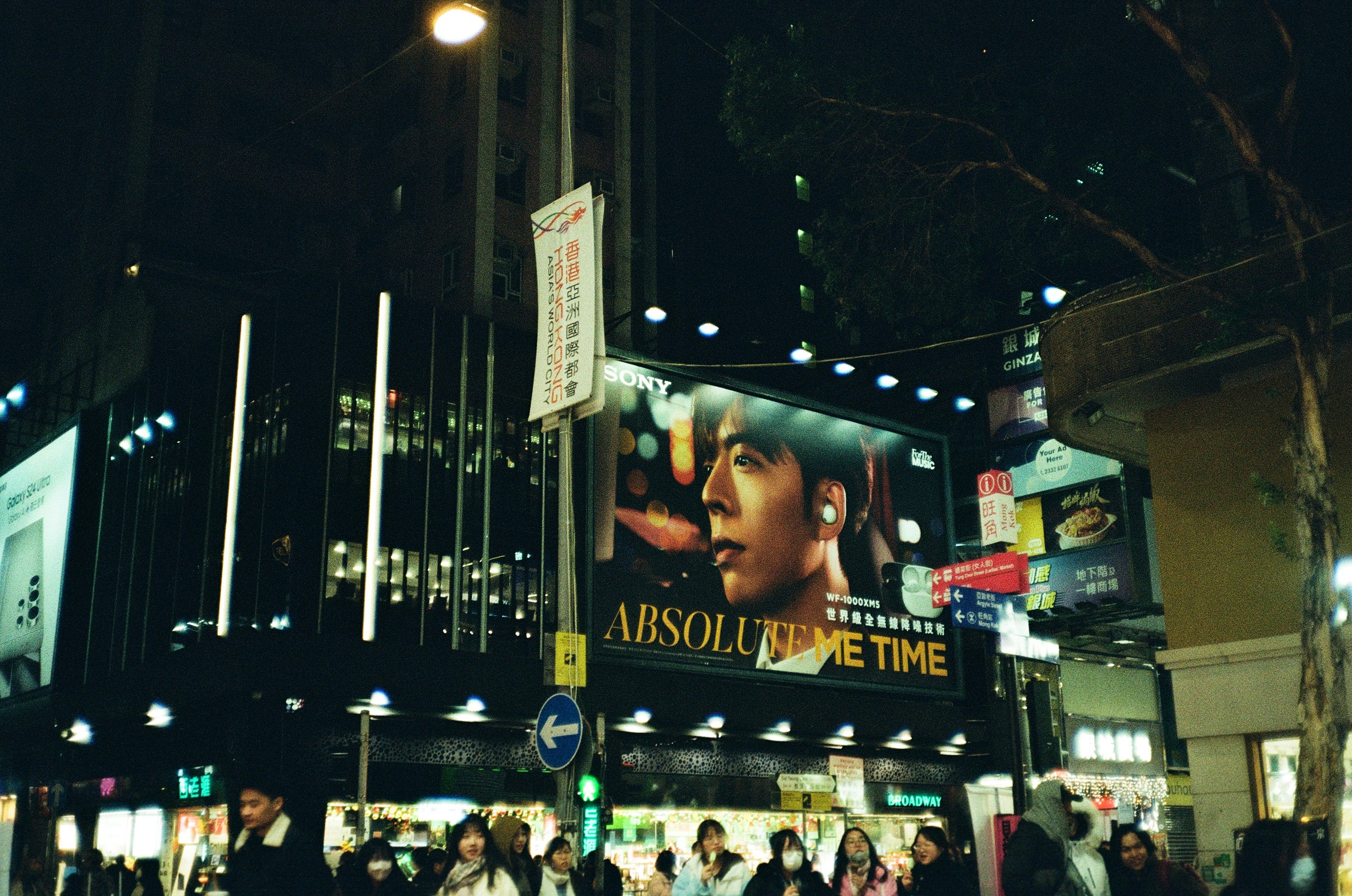 Una multitud de personas caminando por una ciudad por la noche