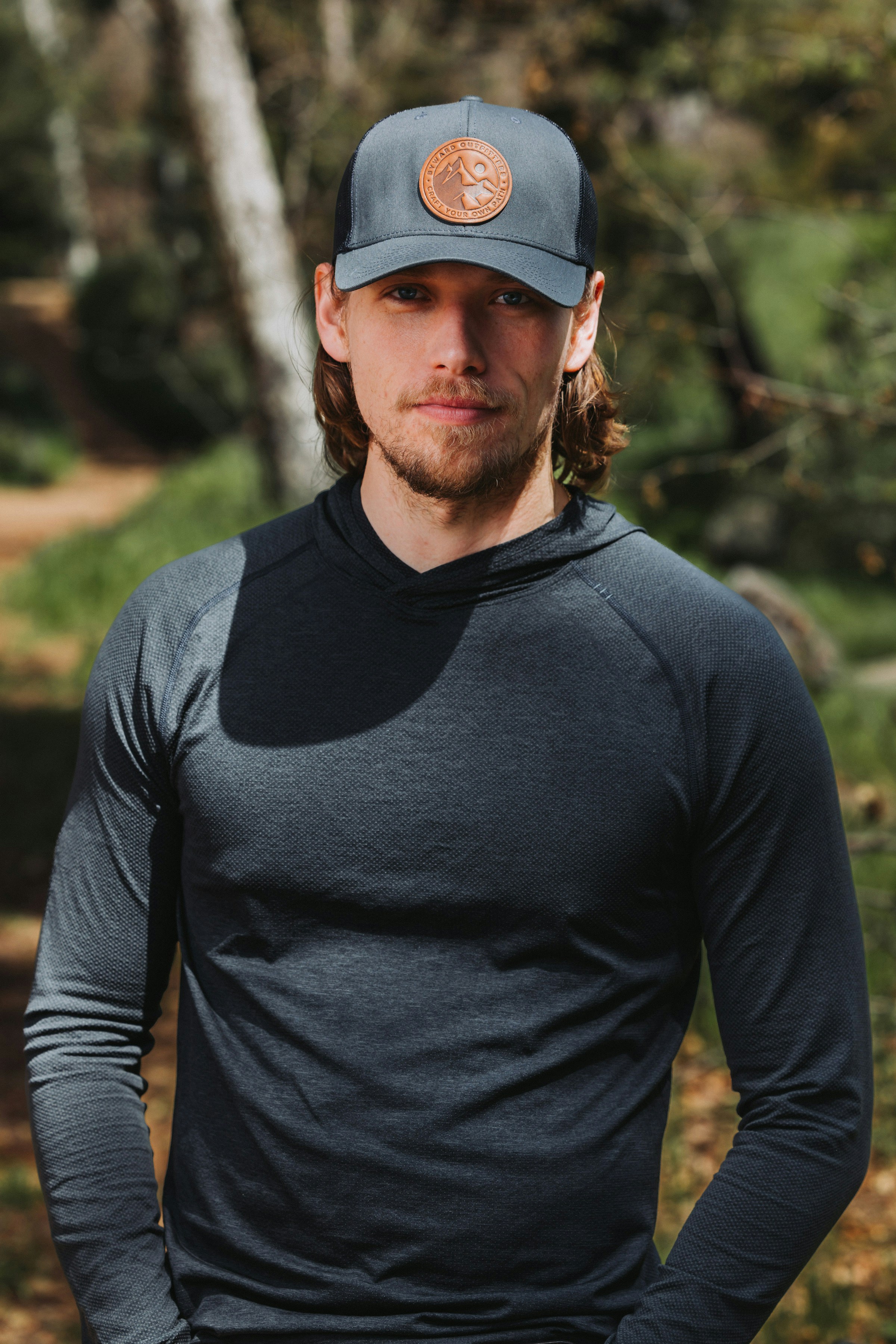 A man wearing a hat standing in the woods