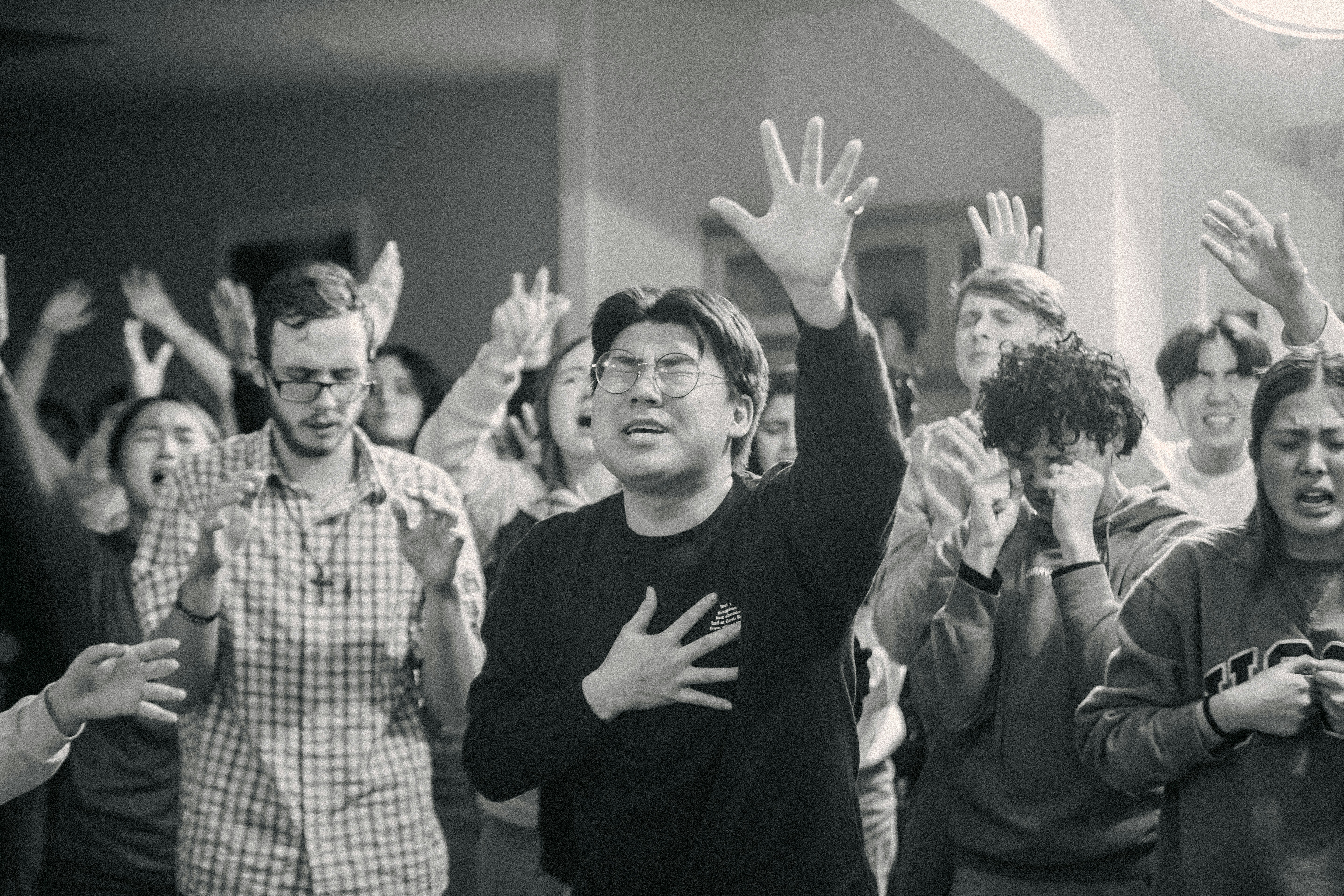 Young diverse group of Christians gathered in church, energetic worship atmosphere, raised hands