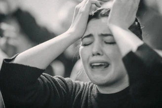 A black and white photo of a woman covering her eyes