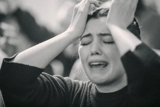 A black and white photo of a woman covering her eyes