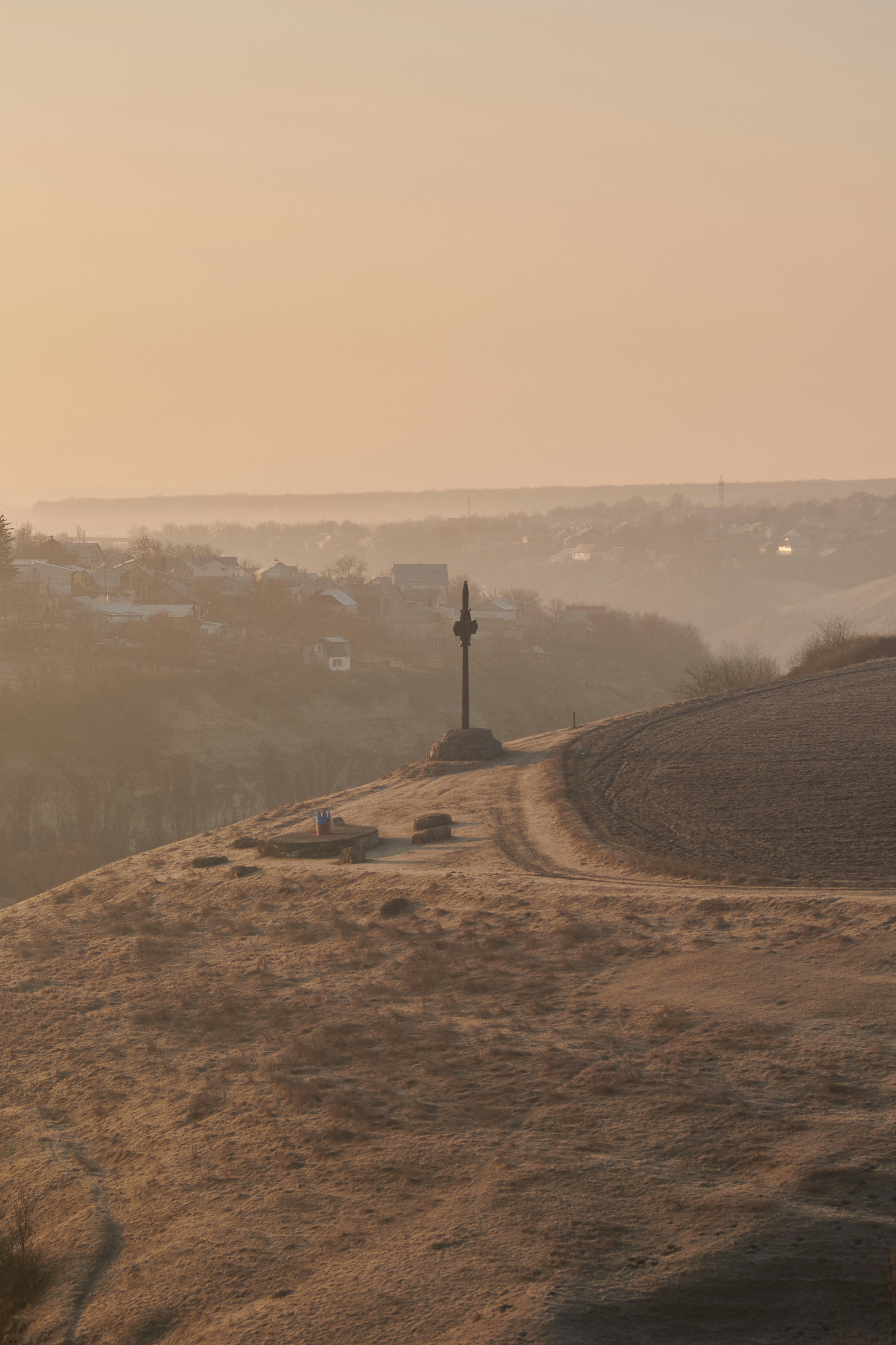 A cross on top of a hill overlooking a town