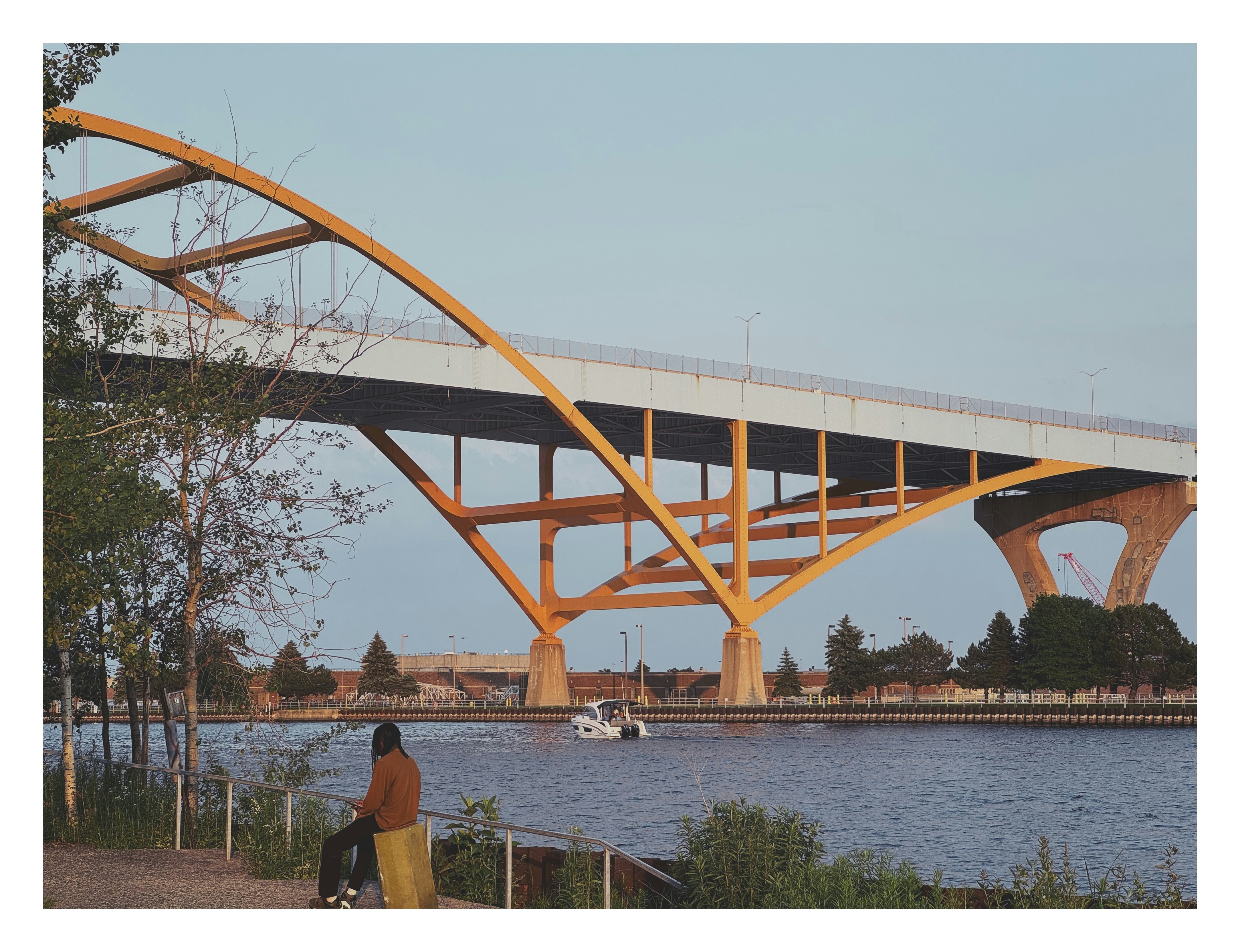 A person walking on a sidewalk near a bridge