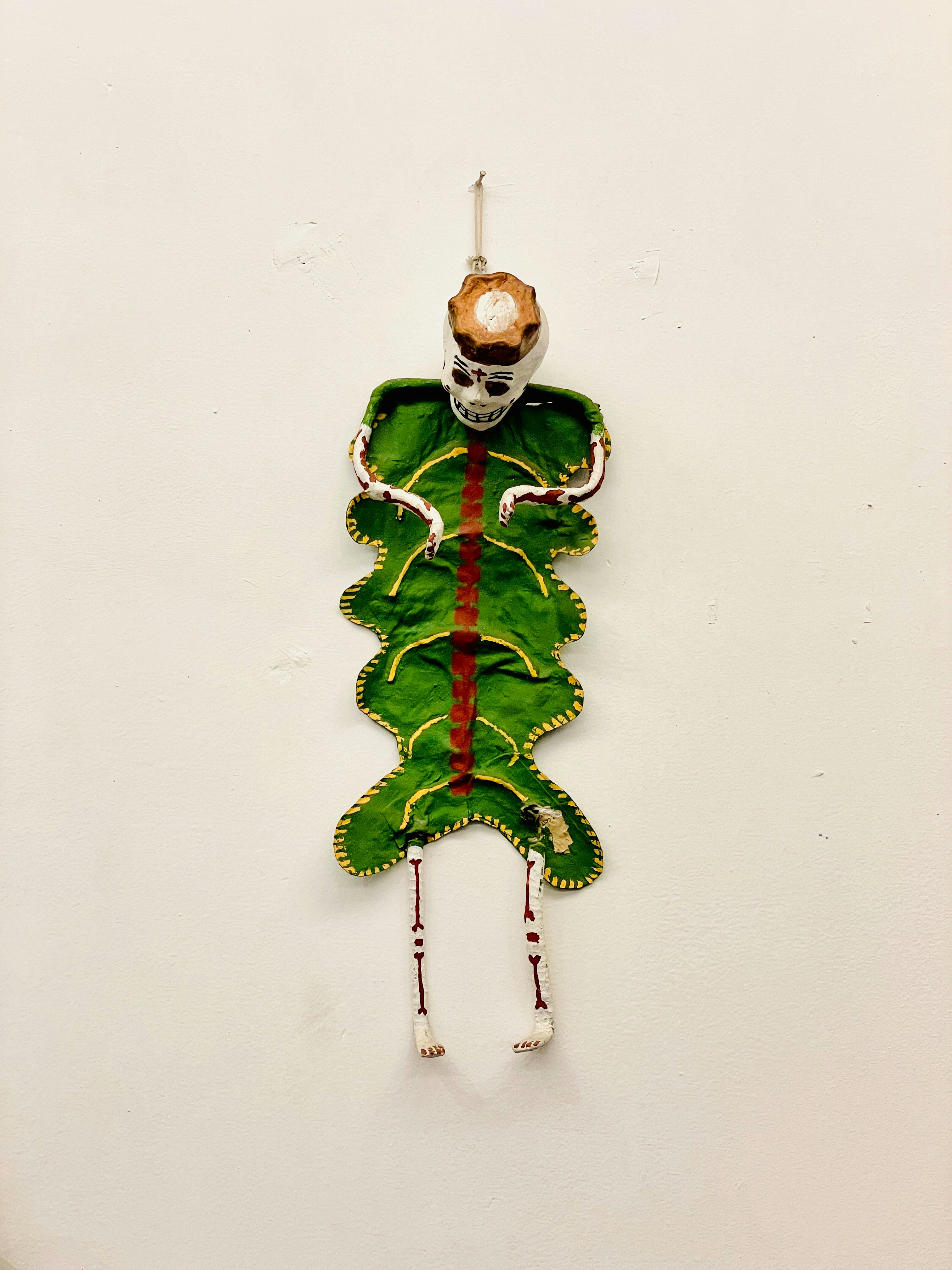 A green and red piece of art hanging on a wall