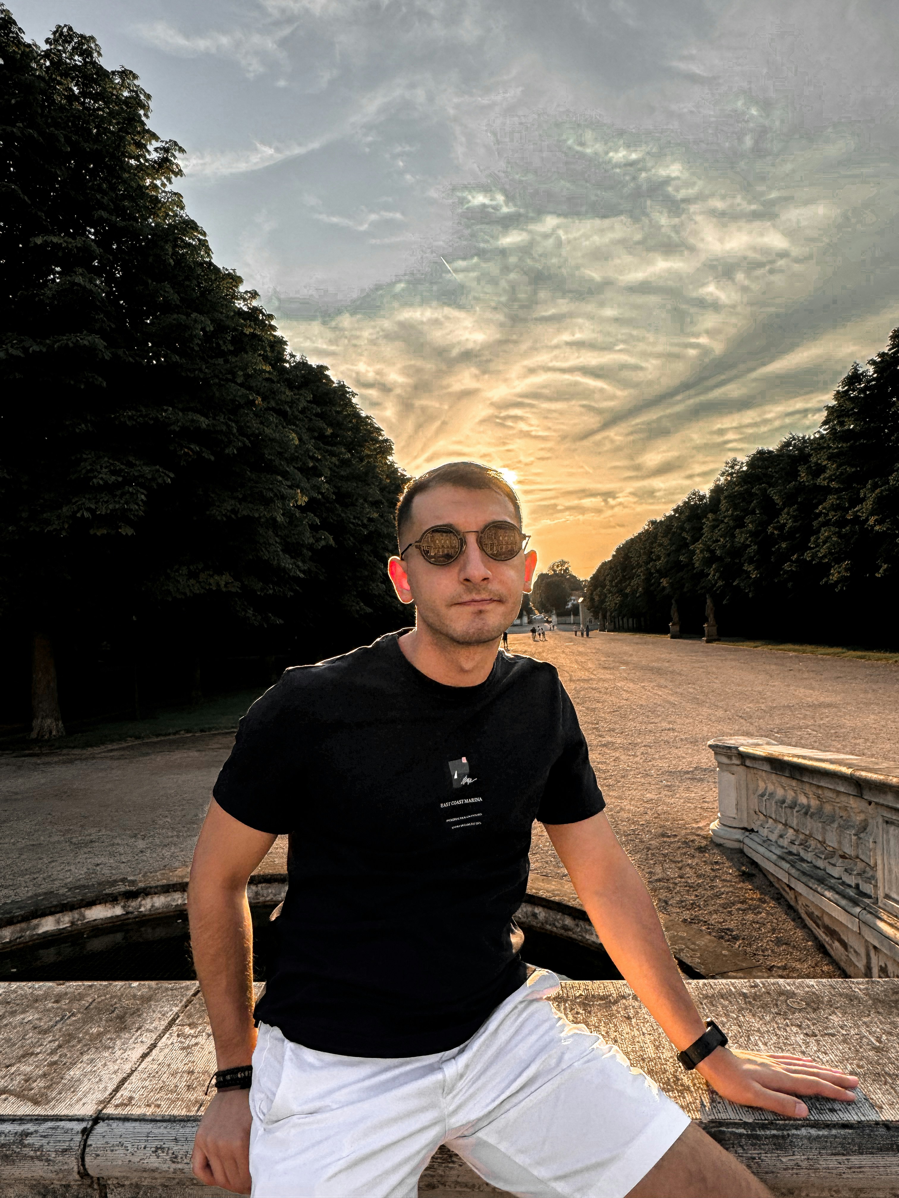 A man in a black shirt and white shorts posing for a picture