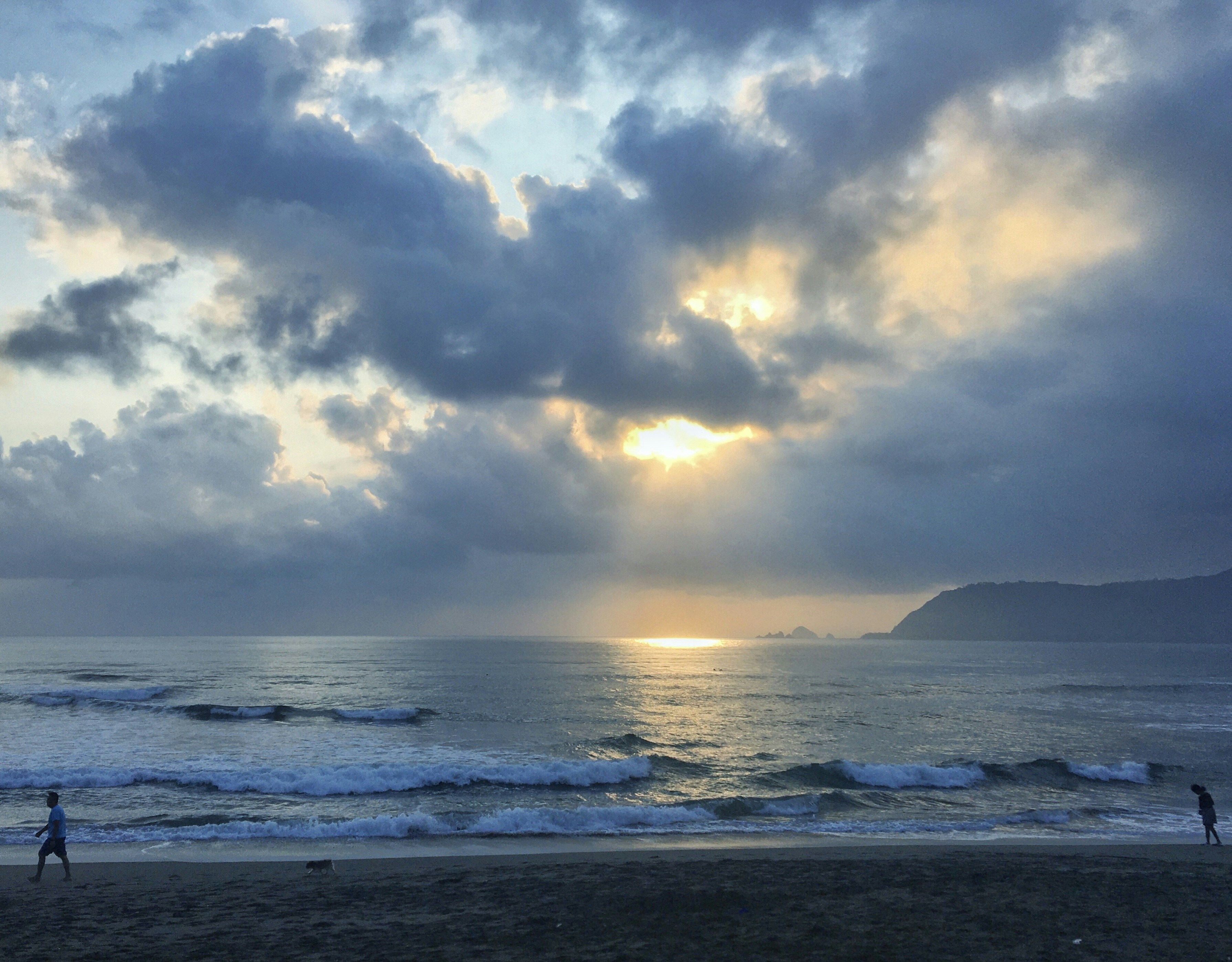 A couple of people standing on top of a sandy beach