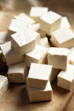 A pile of tofu cubes sitting on top of a cutting board