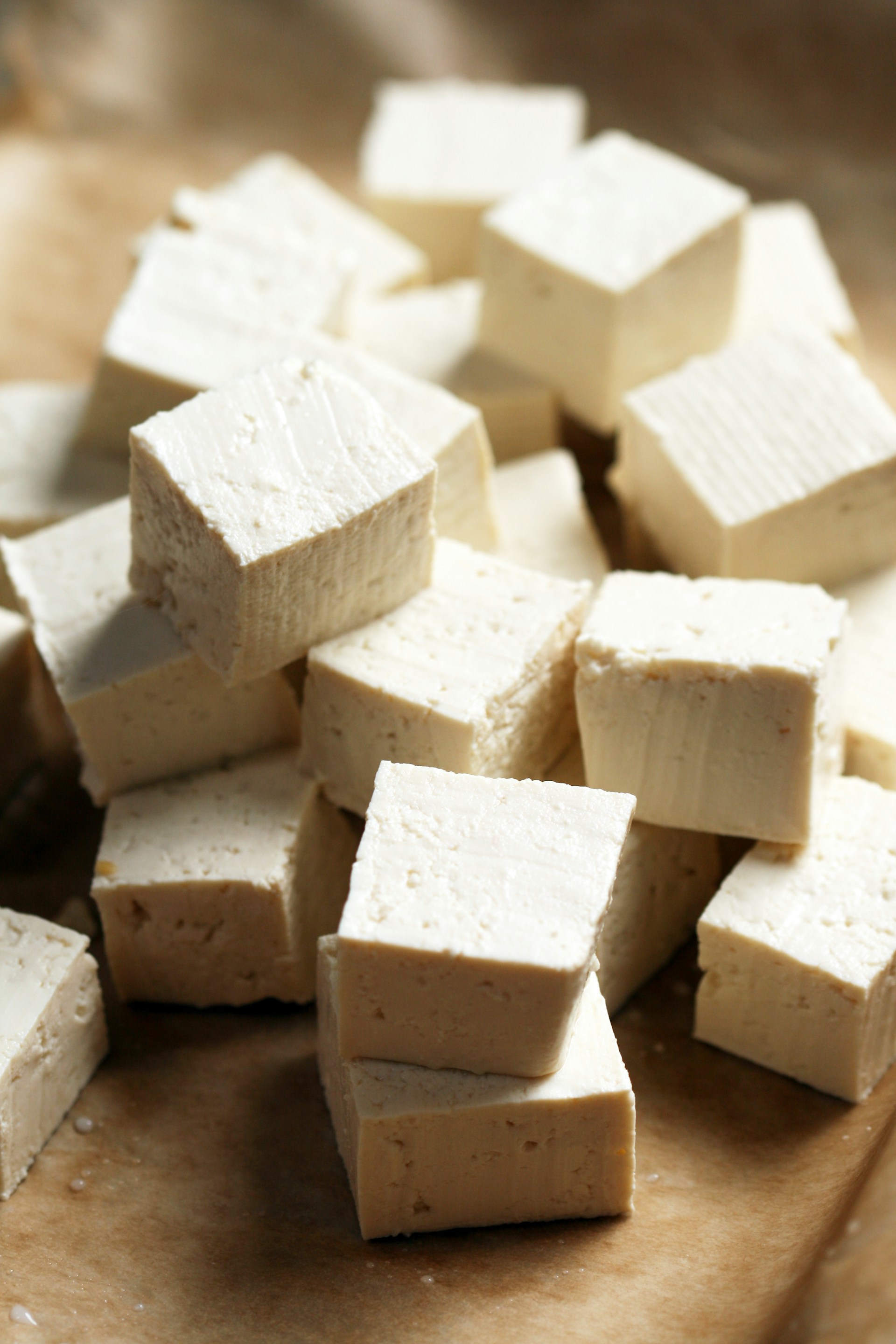 A pile of tofu cubes sitting on top of a cutting board