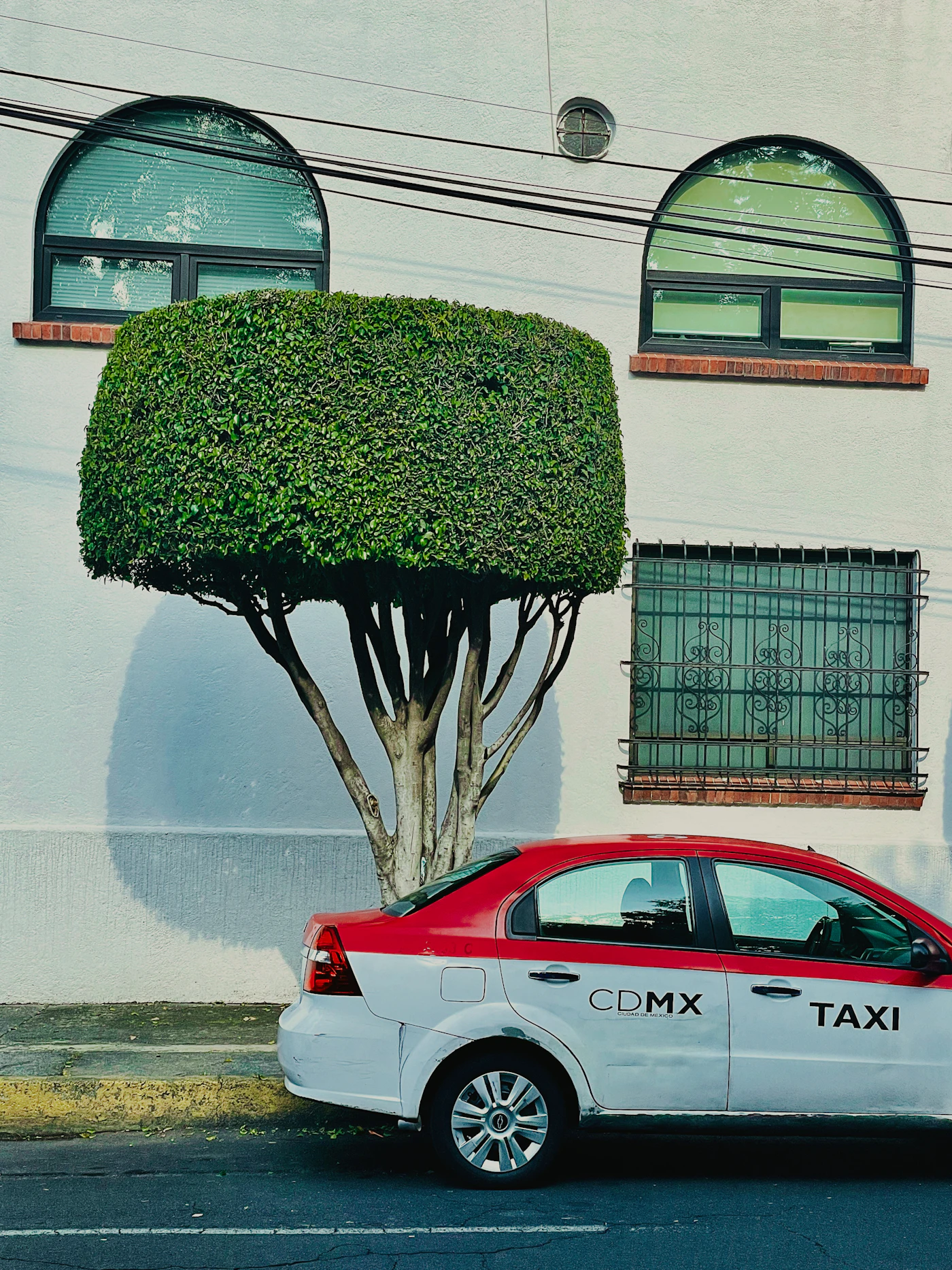 Taxi amarillo estacionado frente a un edificio alto en Ciudad de México durante el día.