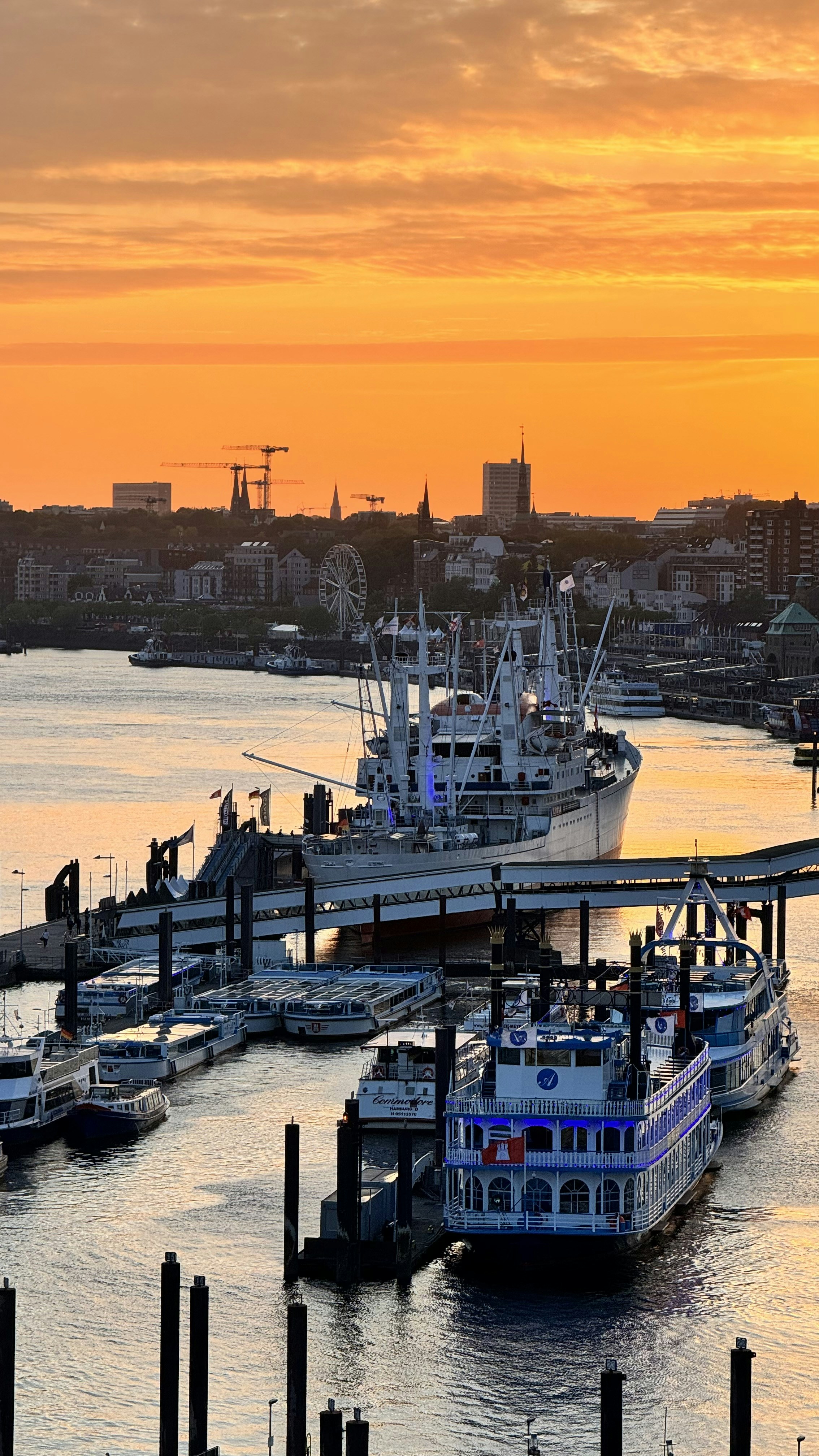 A large boat docked at a pier with a city in the background