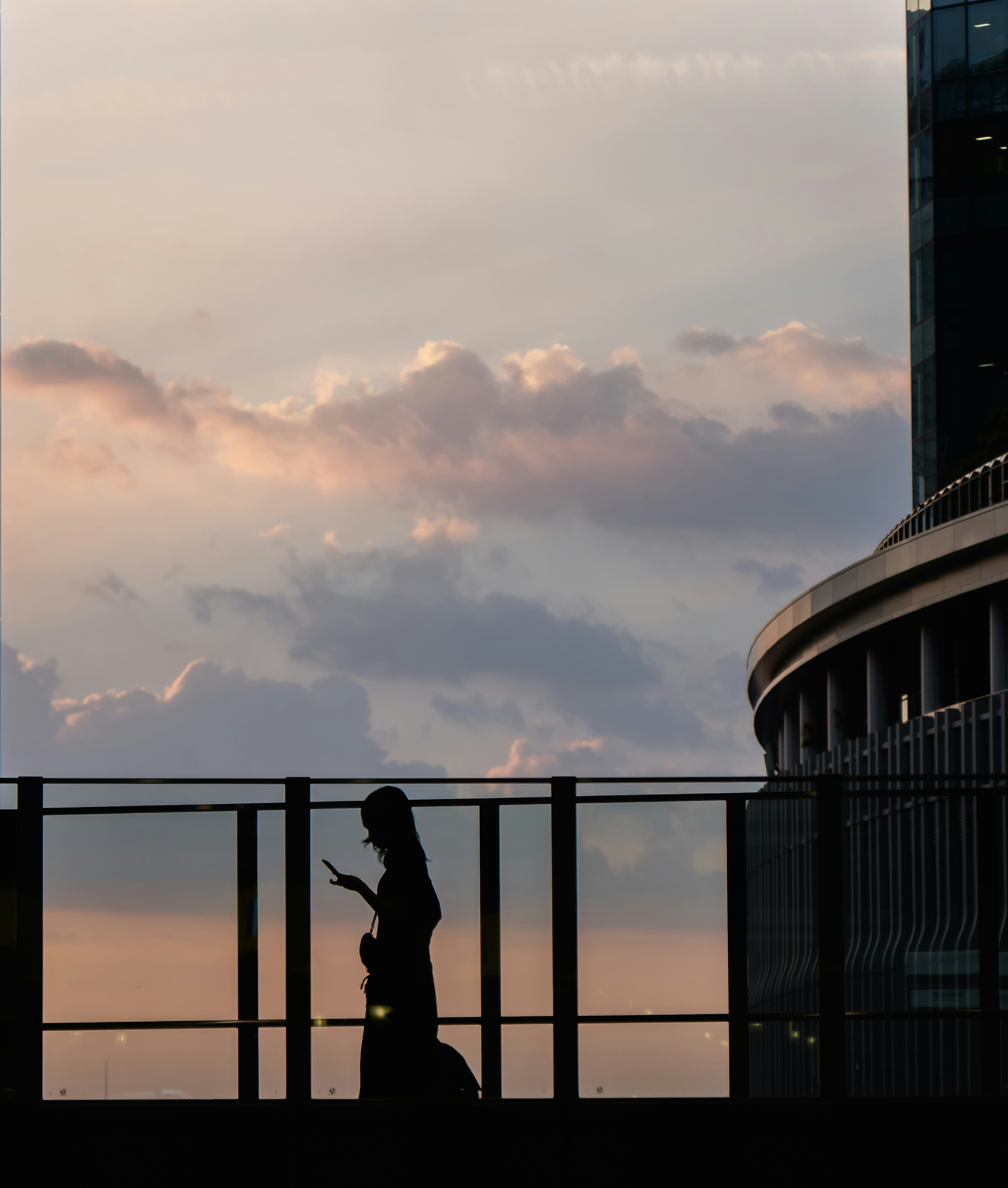 A person walking across a bridge next to a tall building