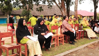 A group of people sitting on top of wooden chairs