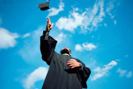 A man in a graduation gown throwing a hat in the air