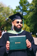 A man in a graduation gown holding a book