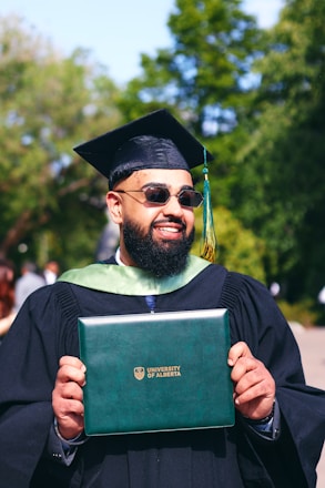 A man in a graduation gown holding a book