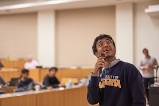 A man holding a microphone in front of a room full of people