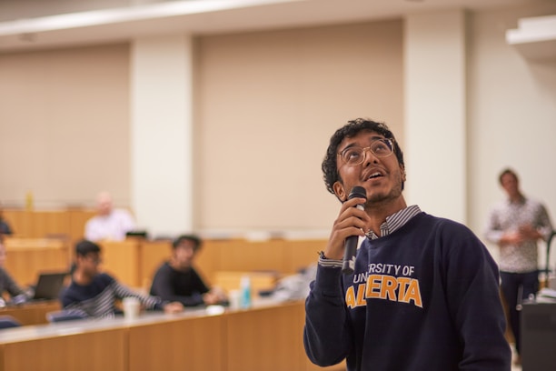 A man holding a microphone in front of a room full of people
