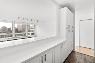 A room with a lot of white cabinets and windows