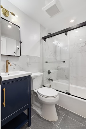 Renovated bathroom with marble tile shower and navy vanity