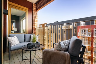 A balcony with a couch, chair, and table on it