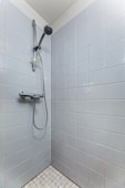 A walk in shower with a hand held shower head