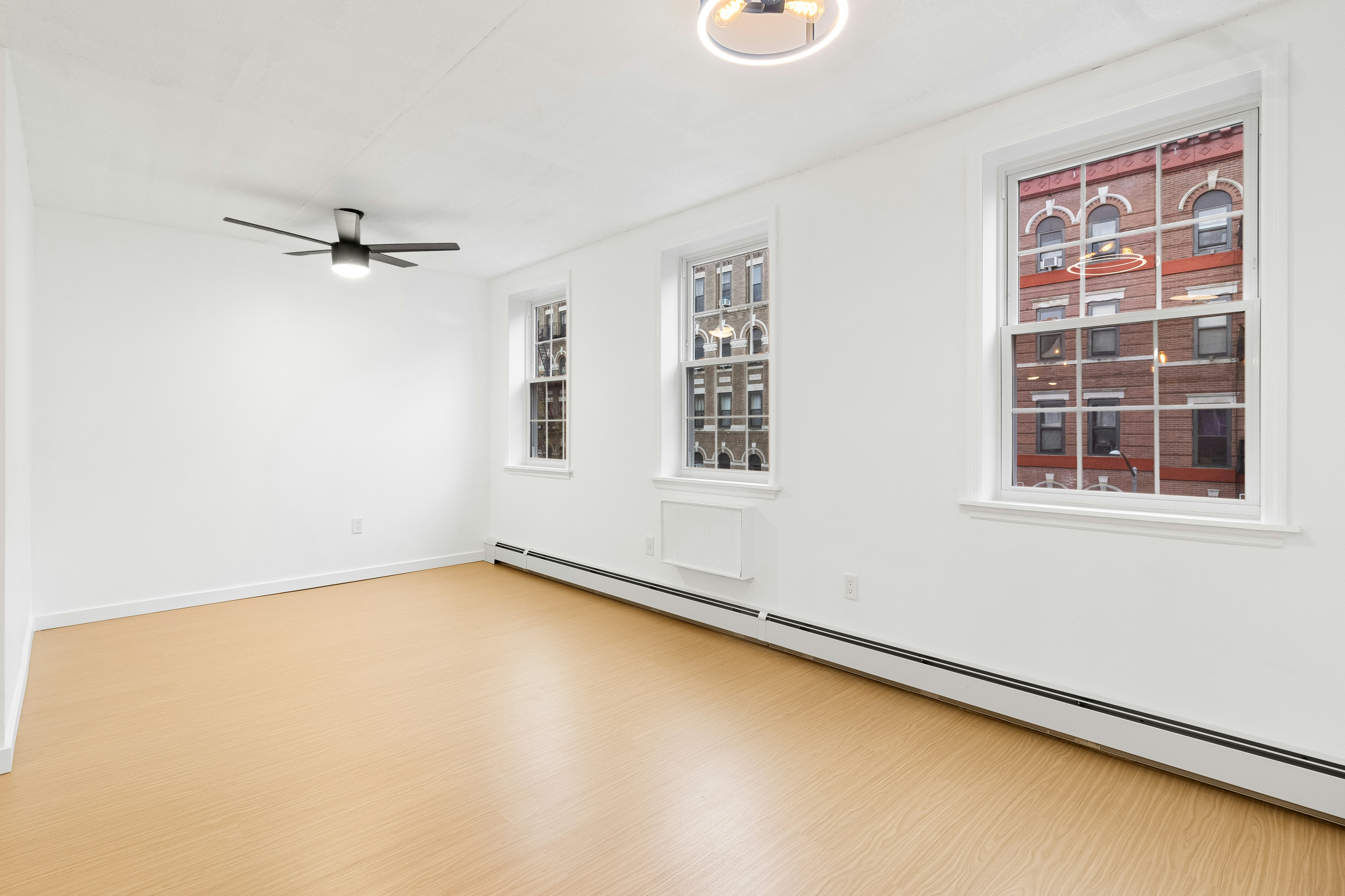Une pièce vide avec un ventilateur de plafond et des fenêtres