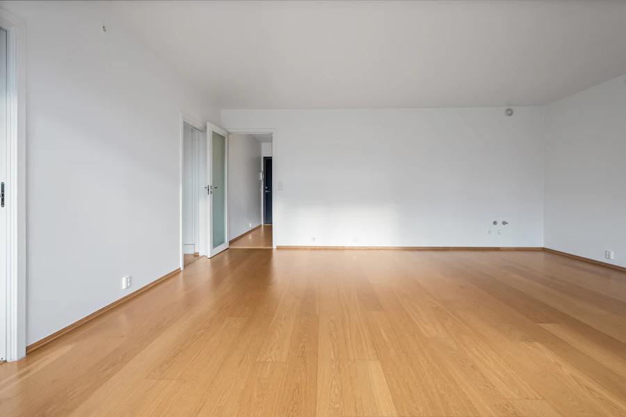 An empty room with clean hardwood floors and bright white walls