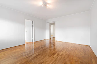 An empty room with hard wood floors and white walls