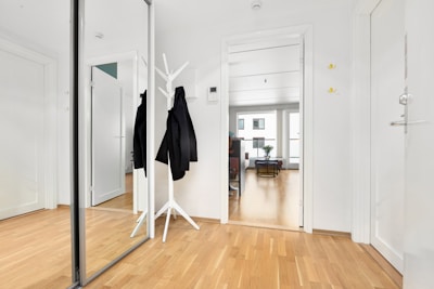 A white room with a mirror and coat rack
