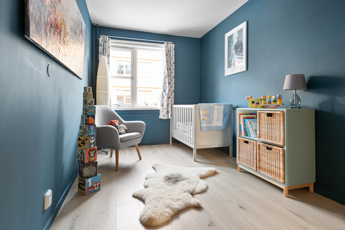 A baby's room with blue walls and a white rug