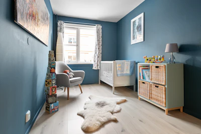 A baby's room with blue walls and a white rug