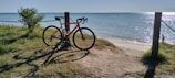 A bike parked on the side of a beach next to the ocean