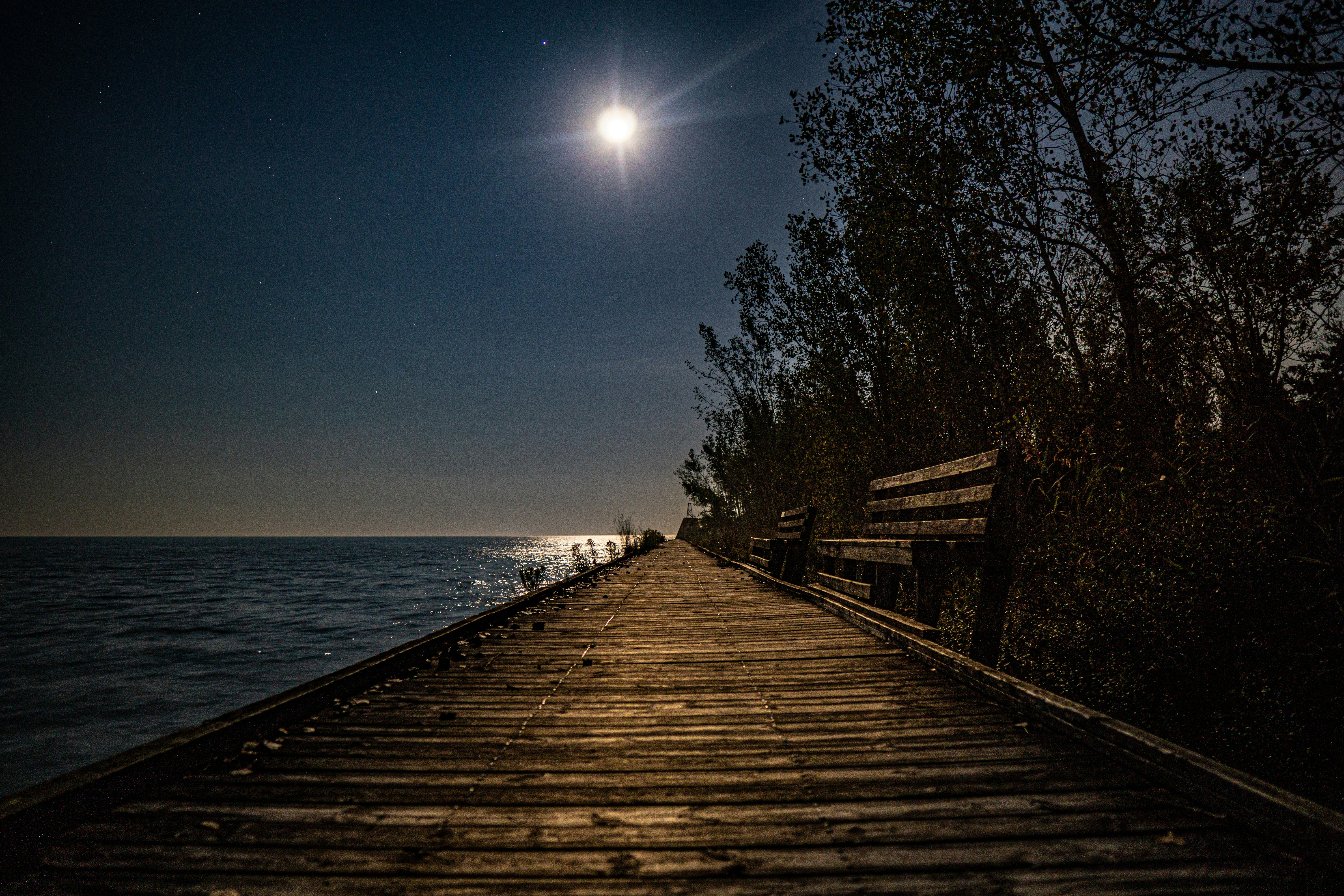A pier with a bench and a full moon in the sky