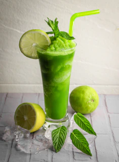 A green drink with limes and mints on a table