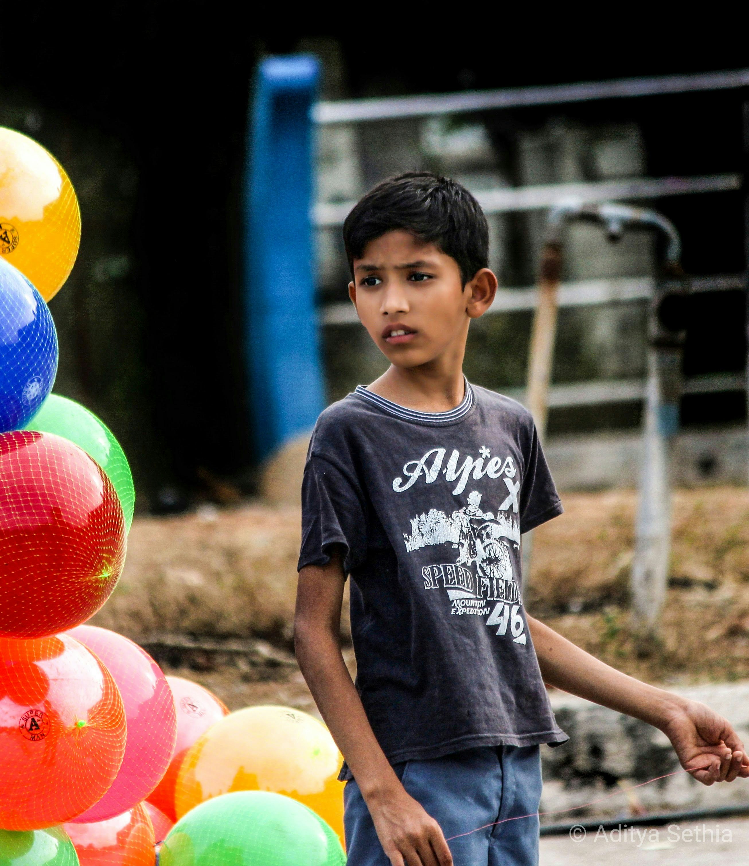 Un niño de pie junto a un montón de globos